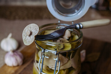 Pickled canned mushrooms in a jar on a cutting Board. Close up. Blurry background.