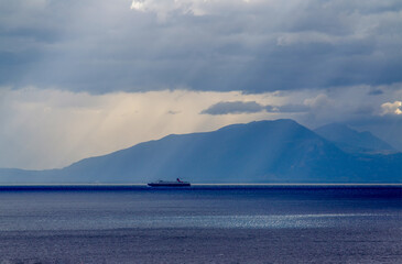 Idyllic seascape in  Tyrrhenian sea . Ship moving to cargo port Salerno and mountain range behind. Amazing Campania