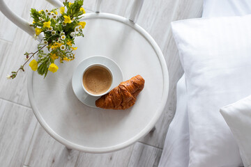 Romantic breakfast in bed. Cup of coffee, french croissant, in the morning, White bedding in the hotel room