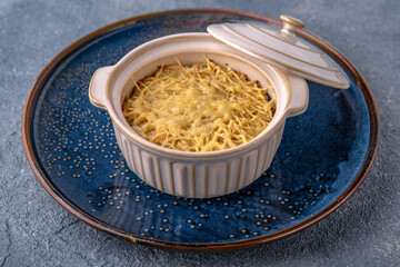 Casserole, risotto, or lasagne with cheese. Natural delicious food. Greek cuisine menu. Still life in a marine style on a blue background.