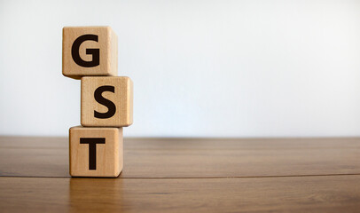 Concept words 'GST, goods and services tax' on cubes on a beautiful wooden table, white background....