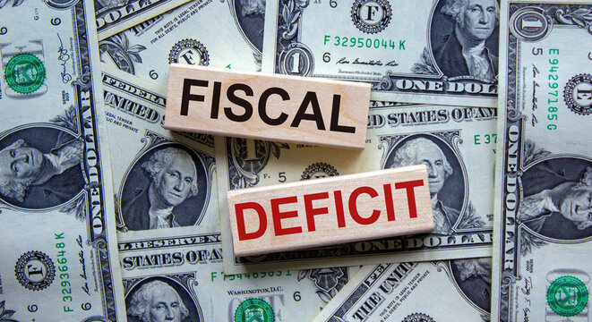 Concept words 'fiscal deficit' on wooden blocks on a beautiful background from dollar bills. Business concept.
