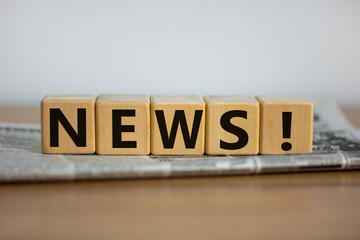 Cubes placed on a newspaper form the word 'news'. Beautiful wooden table. White background. Business concept. Copy space.