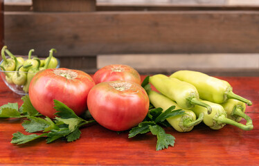 Ripe tomatoes and green paper on a wooden background.