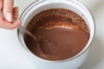 A woman prepares a chocolate ganache. Levington cake, stages of preparation.