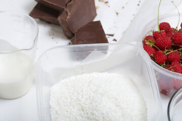 Coconut flakes, next to chocolate and raspberries. Levington cake, stages of preparation.