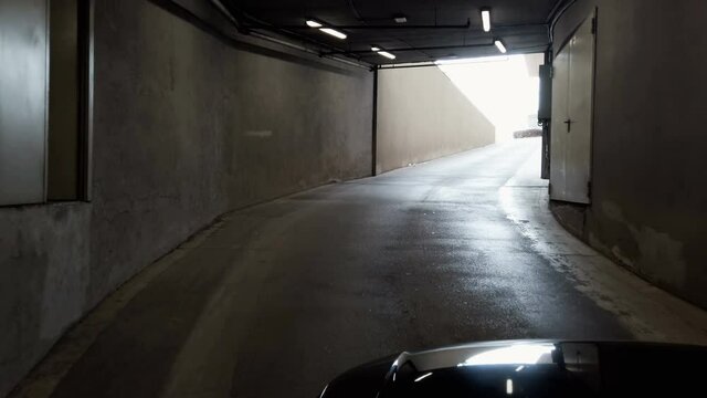 Pov drive through tunnel passage at exit of underground parking garage,real time