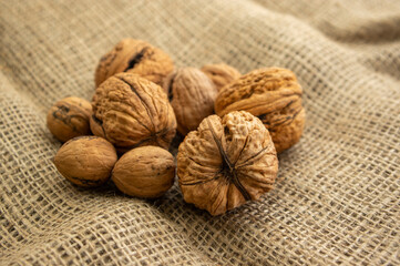 Walnuts on jute table-cloth in hard nutshells, group of dry ripened fruits, crop food ingredients ready for cooking