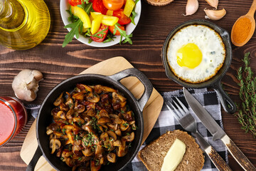 Fried mushrooms and egg in cas-iron skillet. Ingredients for rustic simple food, view from above.