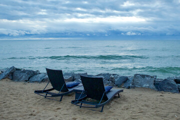 Two chaise lounges on sandy beach along Lake Huron coastline in Michigan at morning
