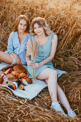 Happy friends on the Golden field. Young girls on a picnic in a wheat field