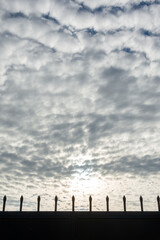 Mackerel sky at sunset behind the silhouette of a spiked fence