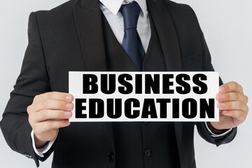 Obraz premium A businessman holds a sign in his hands which says - BUSINESS EDUCATION