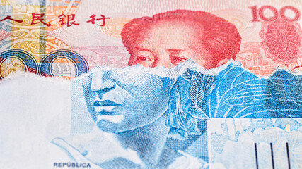 banknote of 100 reais from brazil, torn, revealing a hundred yuan note underneath. Concept of...