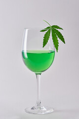 A glass of green hemp-infused wine on white background