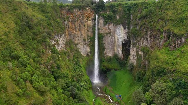 Cinematic aerial view flying away from Sipiso Piso Waterfall in North Sumatra, Indonesia