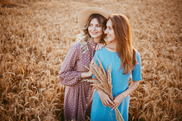 happy friends in a wheat field. girls on a picnic in a field at sunset.