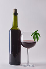 A bottle and a glass of cabernet with hemp infusion on white background