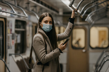 A woman in a medical face mask to avoid the spread of coronavirus is looking around in a subway...