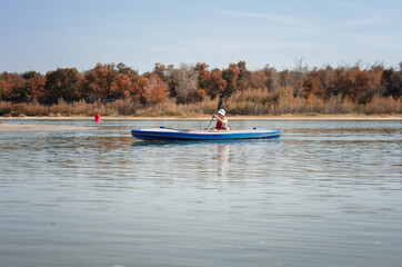 Young man kayaking on wide river, summer healthy outdoor recreation