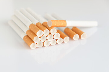 Cigarettes with a yellow filter lie on a white surface