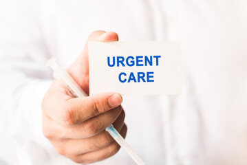 Word urgent care on a white background with a syringe in hand. Medicine concept