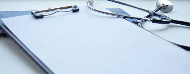 Medical stethoscope and clipboard with a blank sheet of paper. Medical concept. Selective focus.