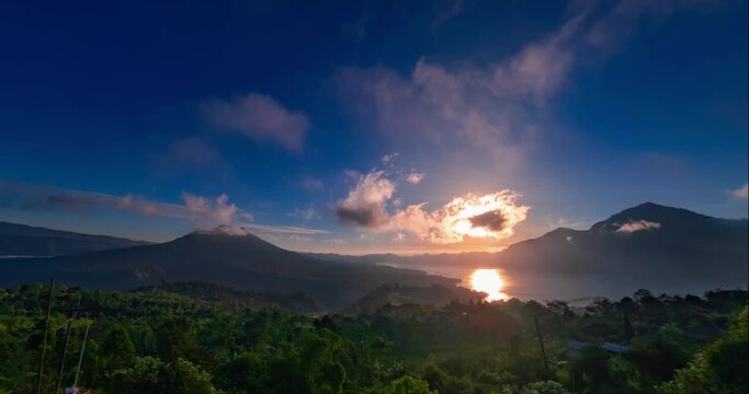 Hyperlapse of sunrise with view on Batur and Abang volcanoes and lake on Bali. Clouds are moving fast in blue sky, the sun is rising