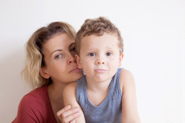 Portrait of happy mother with cute kids boy sitting on a light background. Happy family concept.