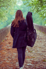 Young girl carry guitar bag while walking alone in naure