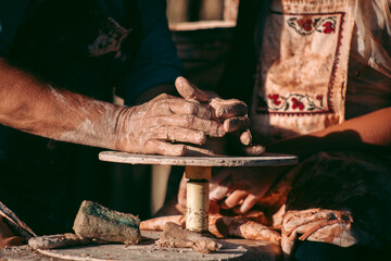An experienced potter teaches an apprentice to work with clay and a potter's wheel