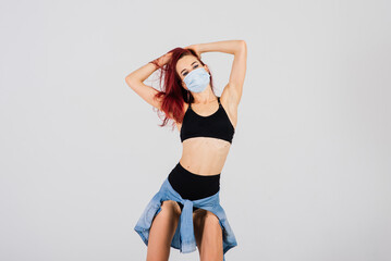 Female dancer in the styles of strip-plastic and pole dance with face mask on light background.