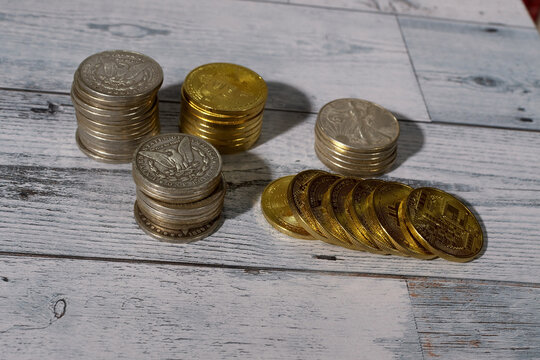 Selective focus image of staks of silver dollars and a toppled stiack of gold coins..  Financial risk concept.