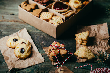 Dark moody gingerbread cookies for Christmas in a small paper box decorated on rustic green table. 