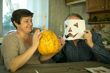 The pumpkin is ready for slicing. The man and the woman are happy with their work and laugh and...