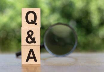 concept of the word Q&A on cubes on a wooden table with green background