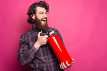 Photo of bearded man screaming and using Red Fire Extinguisher to stop fire