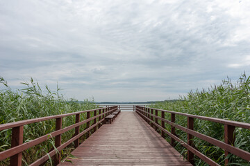 Fototapeta na wymiar Wooden pier under cloudy sky on Lake Jamno, Mielno, Poland. 