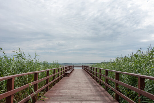 Wooden pier under cloudy sky on Lake Jamno, Mielno, Poland. 