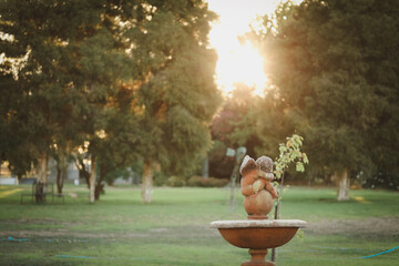 Stone cherub statue with bird bath in beautiful garden setting at sunset