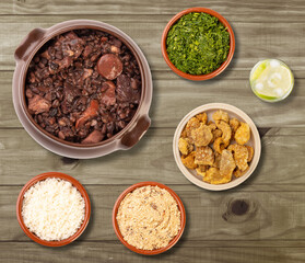 Typical brazilian feijoada with caipirinha and side dishes over wooden table