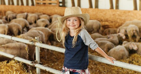 Portrait of Caucasian blonde pretty girl with fair hair standing at fence in stable and smiling to...