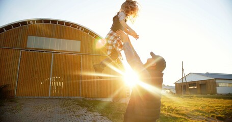 Caucasian young handsome father playing with small cute daughter and tossing up in air. Outdoor in...