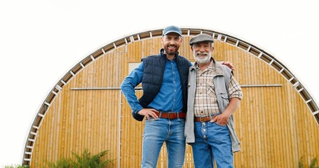 Caucasian young man standing outdoor with old retired father in farm and talking, asking for...