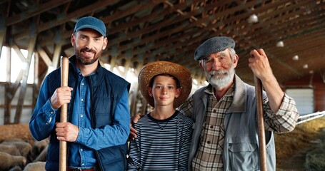 Three male generations in green field at cattle farm. Caucasian grandfather, father and son smiling...