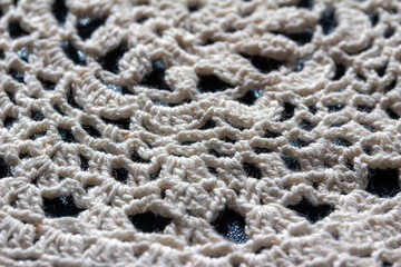 Full frame macro art abstract view of a white crocheted yarn doily texture on a dark blue background, with copy space