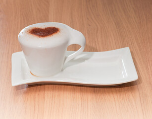 Cup of coffee with cinnamon heart on milk foam