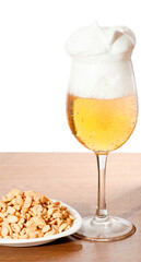 Glass of cold beer and nuts over wooden surface