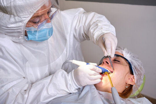 Female Dentist Drilling Tooth To Patient In Lock Down