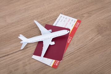 A small white airplane model on a passport holding an airplane ticket